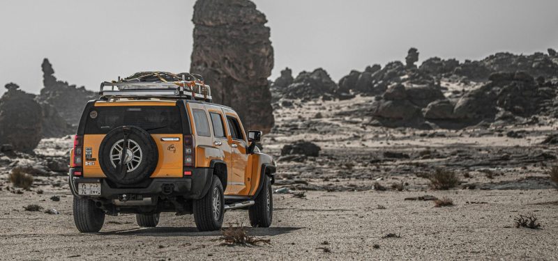 Yellow SUV exploring rugged desert terrain with rocky formations.