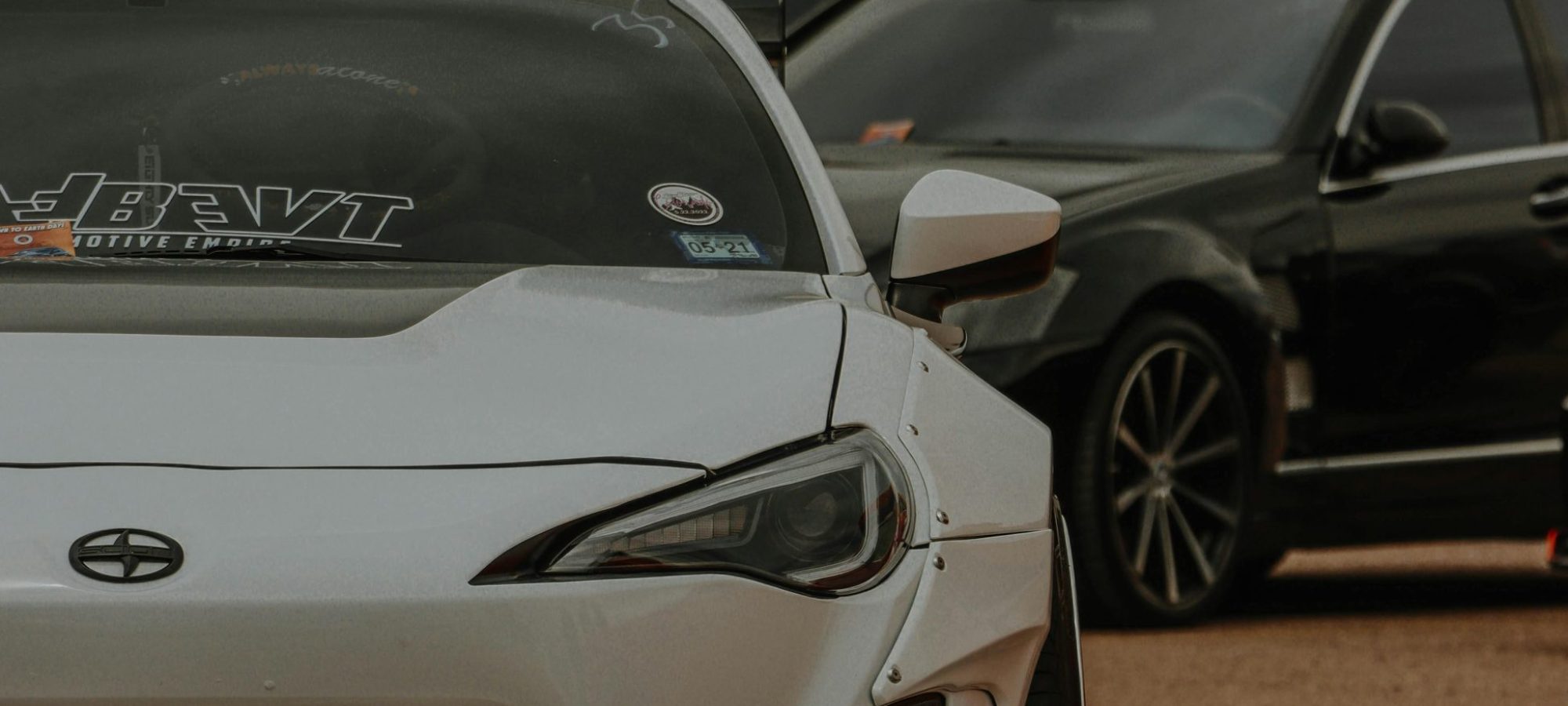 A white scion parked at an outdoor auto exhibition with other vehicles around. by Jacob Moore via pexels