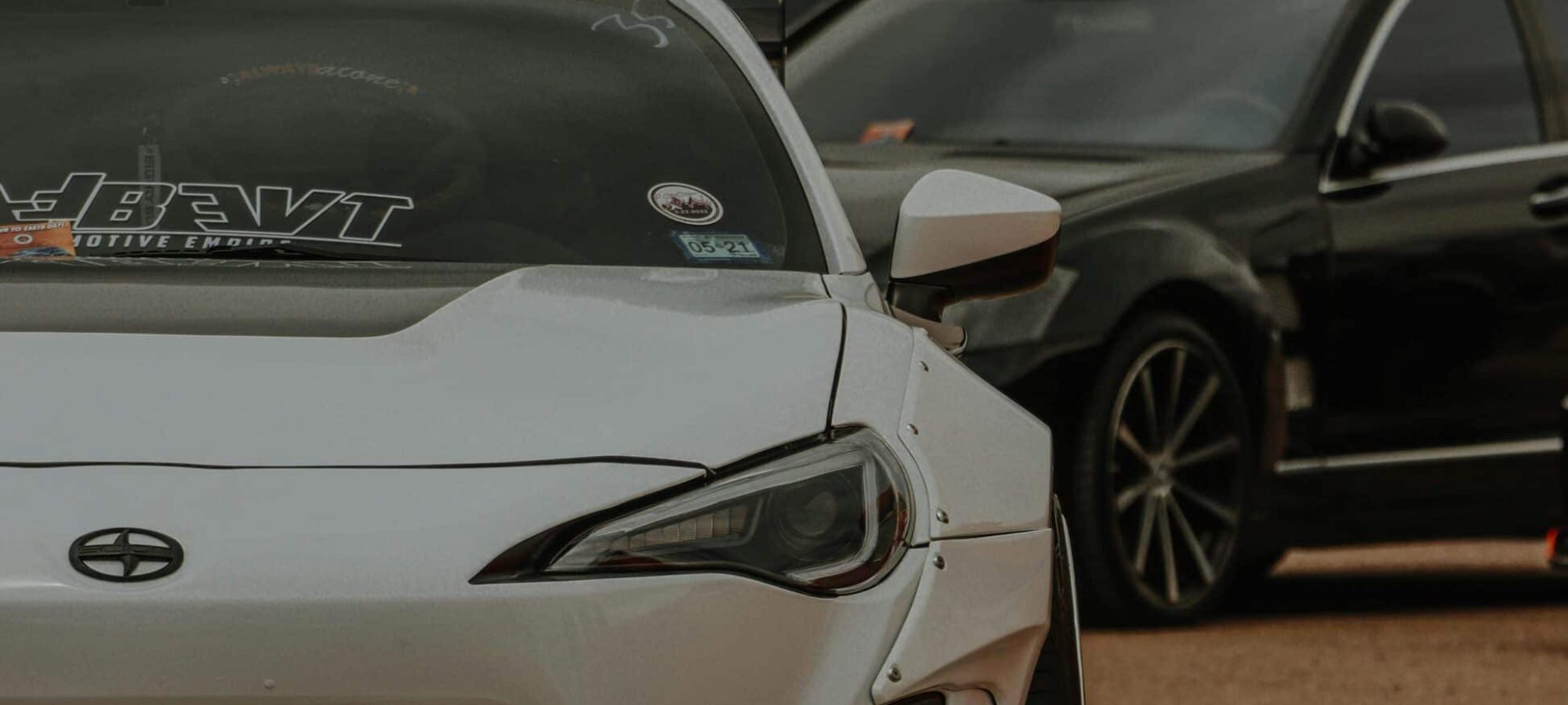 A white scion parked at an outdoor auto exhibition with other vehicles around. by Jacob Moore via pexels