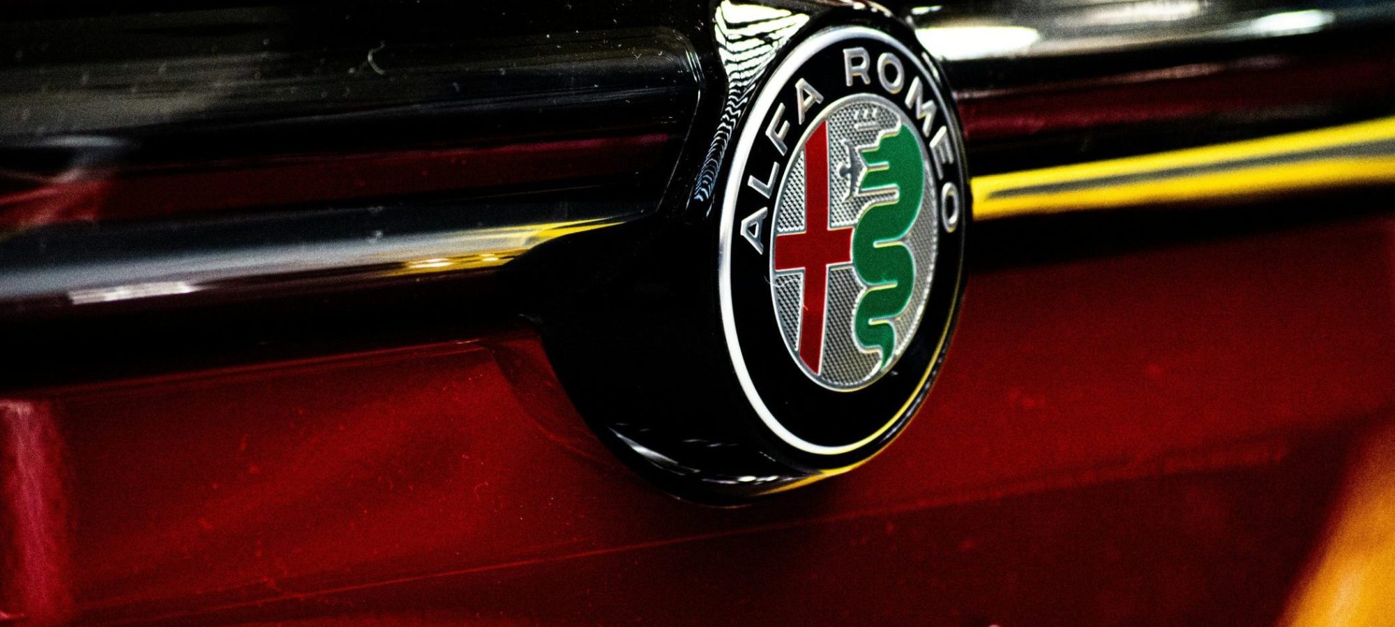 Detailed image of the Alfa Romeo Tonale logo on a red car.