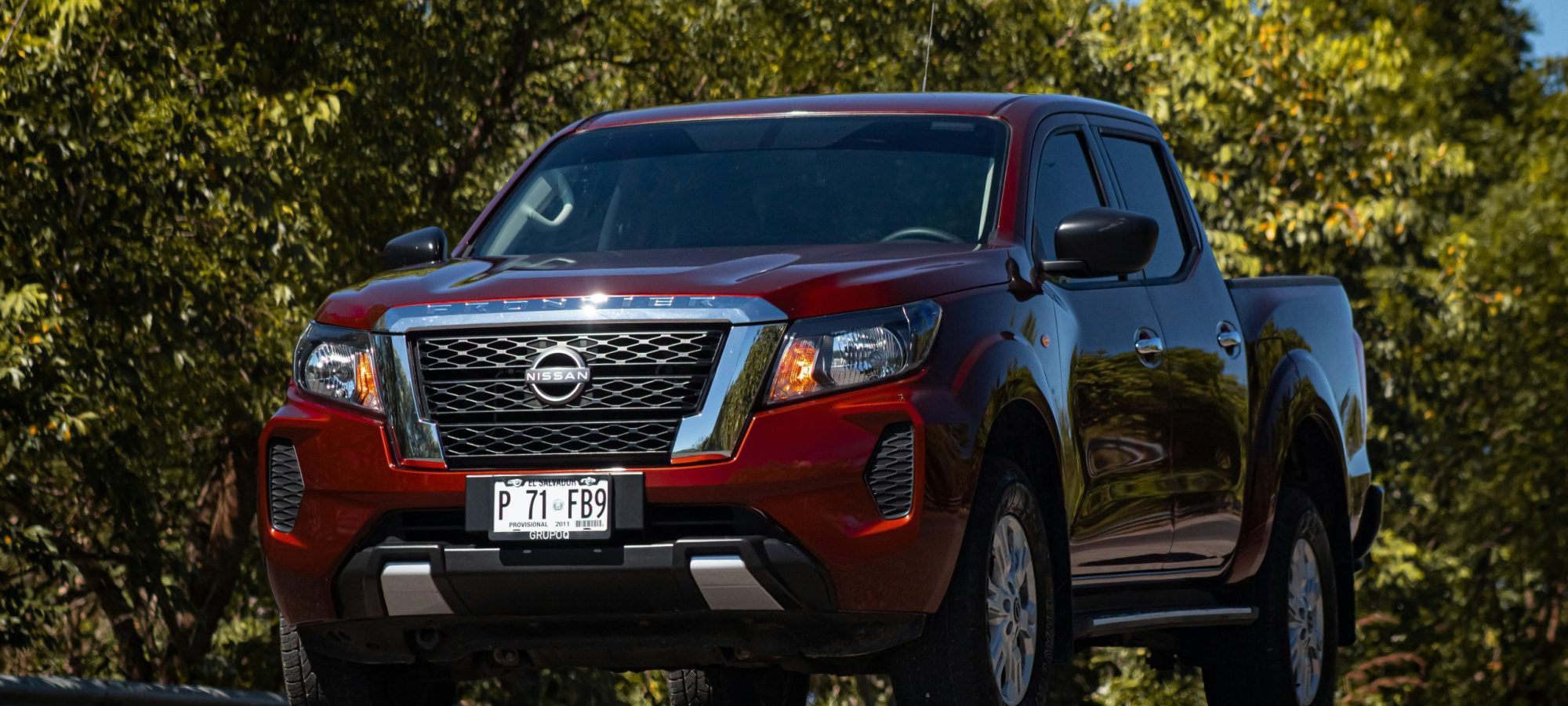 Nissan Frontier red pickup truck captured outdoors on a scenic road. by Cristian Villafranco via pexels