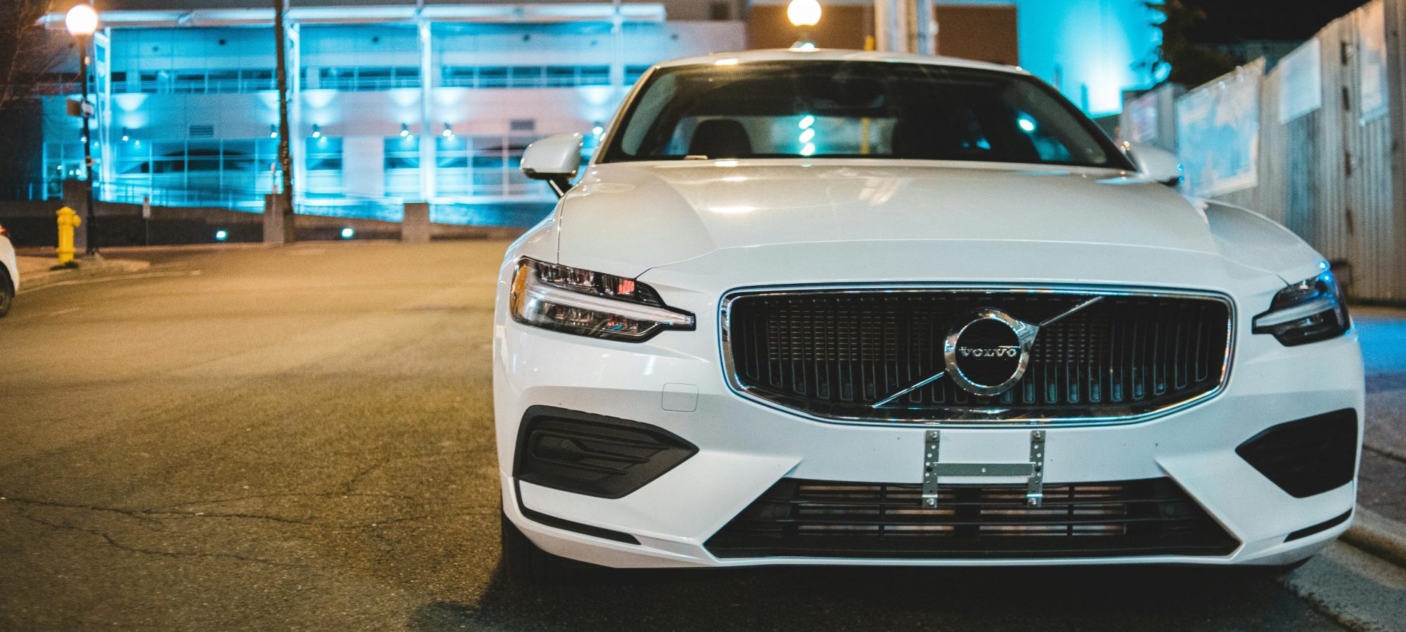 Front view of a white Volvo car parked on the roadside at night under urban lights. by Erik Mclean via pexels