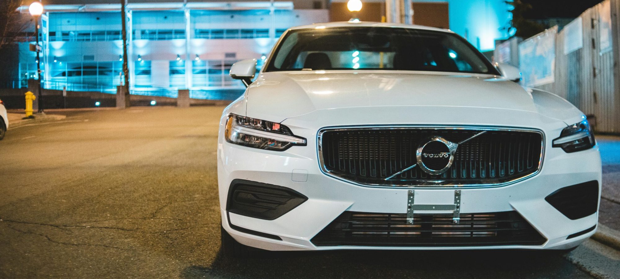 Front view of a white Volvo car parked on the roadside at night under urban lights. by Erik Mclean via pexels