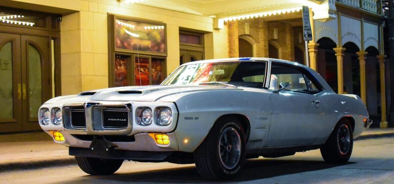 Vintage Pontiac Firebird Trans Am parked on a lit street at night.