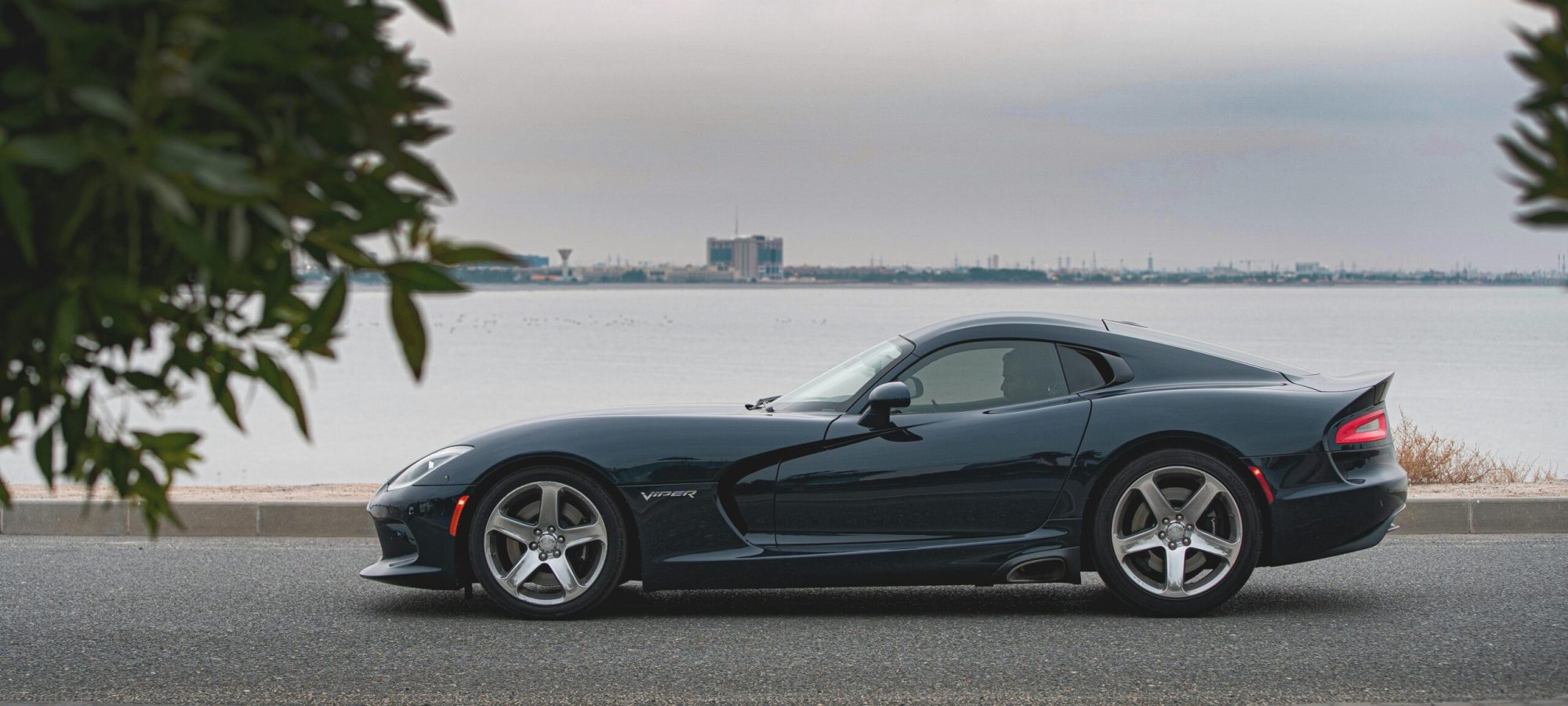 SRT VIPER parked by a waterfront road, showcasing elegance and modern design. by Abdulwahab Alawadhi via pexels